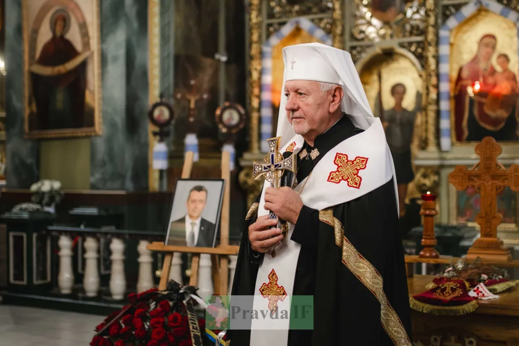 Священнослужитель із хрестом біля портрета померлого в церкві