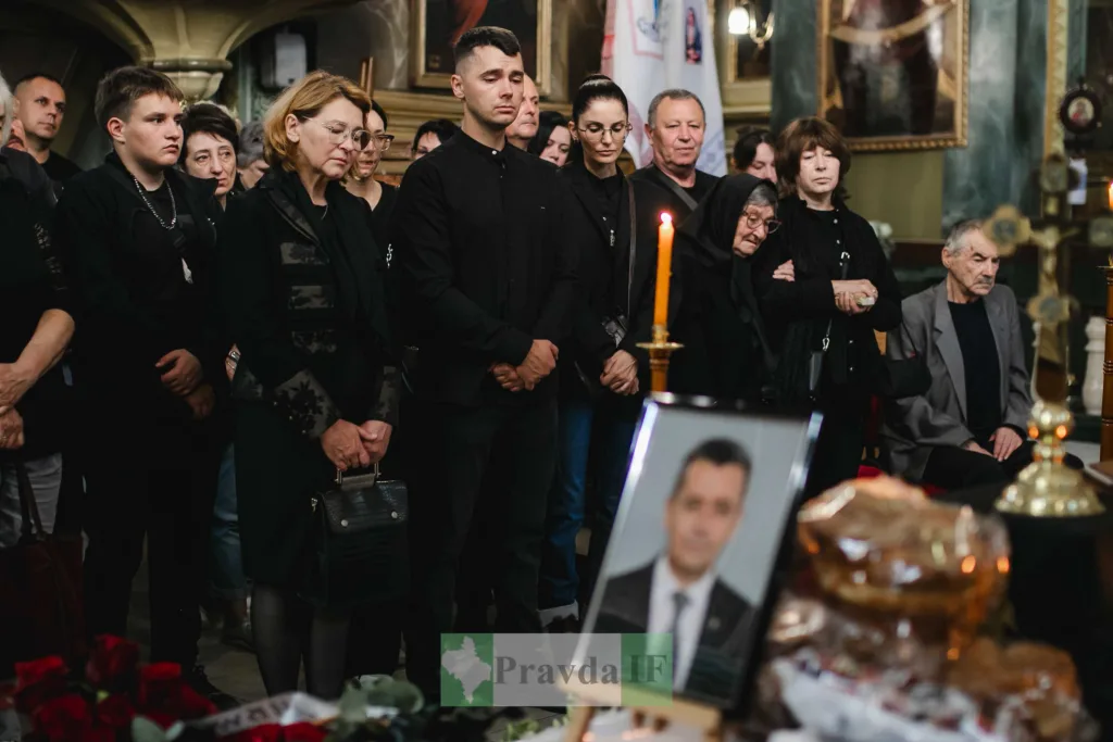 Люди в чорному прощаються біля труни в церкві