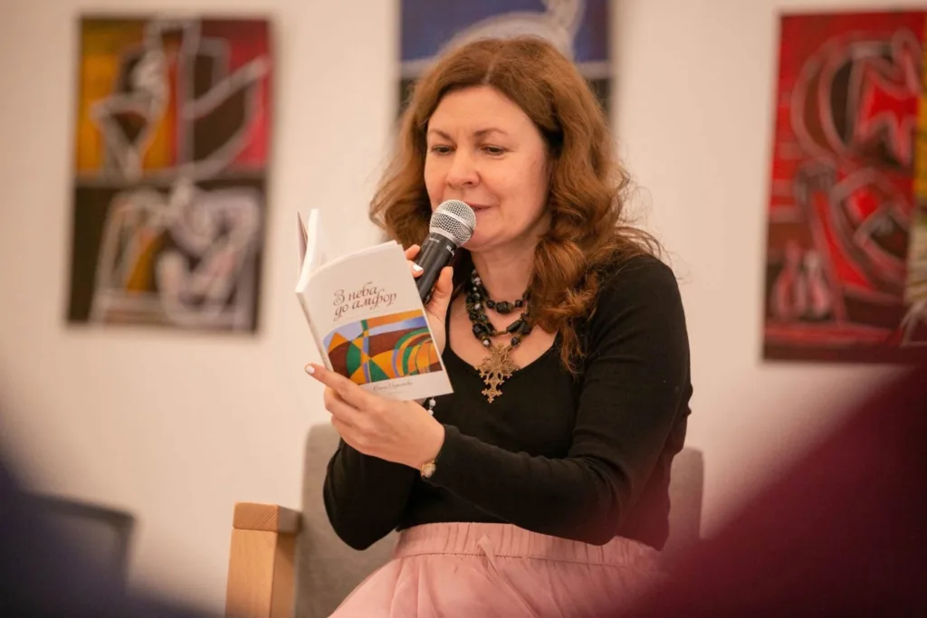 Жінка читає книгу в мікрофон на мистецькому заході