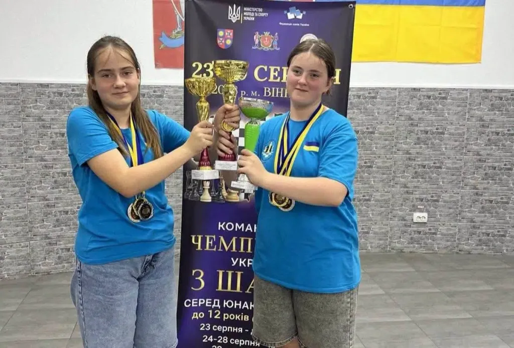 Дві юні спортсменки з кубками та медалями