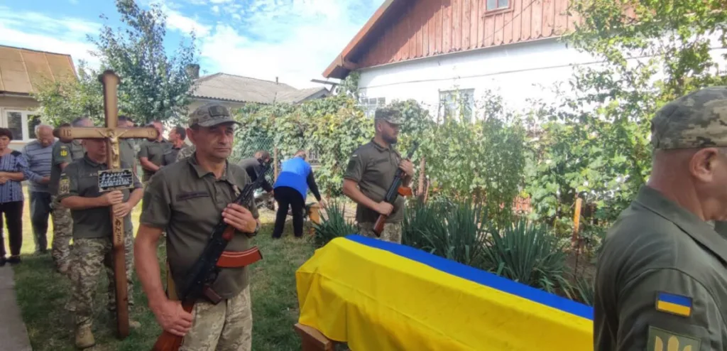 Військові біля труни, вкритої українським прапором