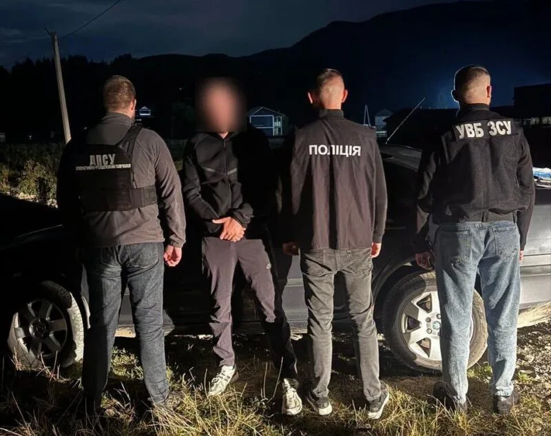 Правоохоронці затримують чоловіка біля автомобіля вночі