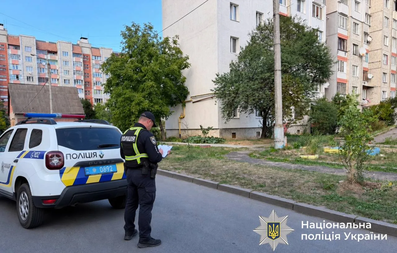 Поліцейський біля службового авто у житловому дворі