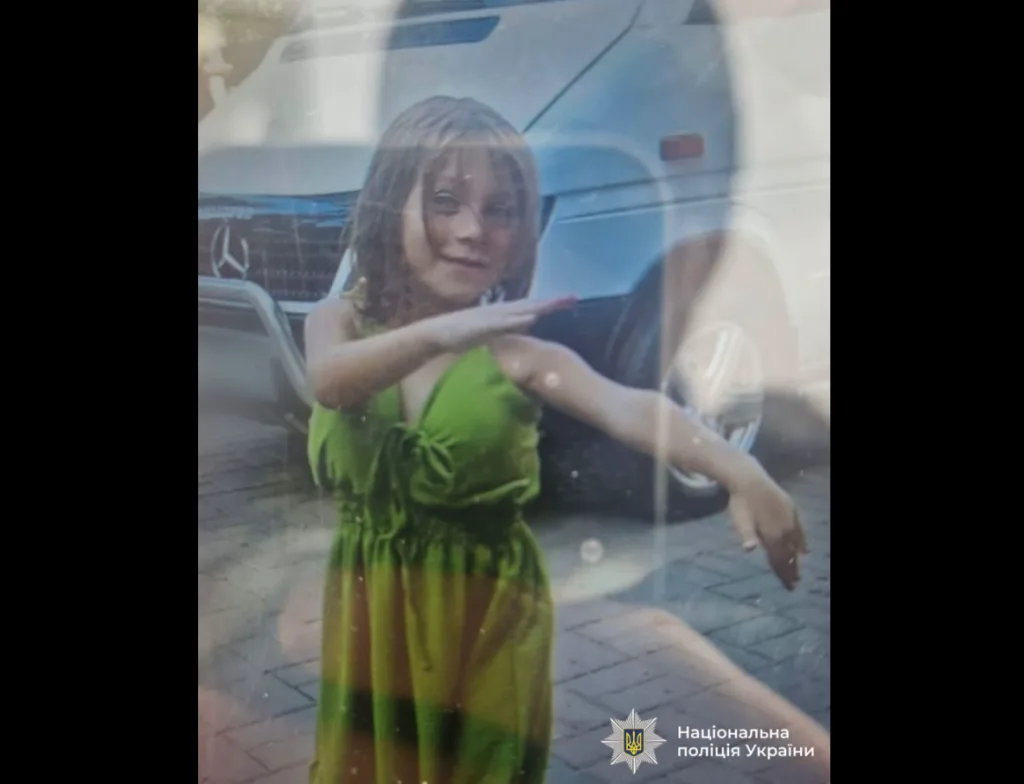 Дівчина в зеленій сукні біля білого мікроавтобуса
