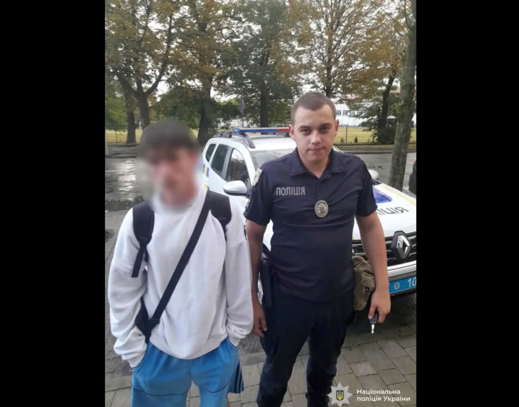 Поліцейський стоїть поруч із чоловіком біля патрульного авто