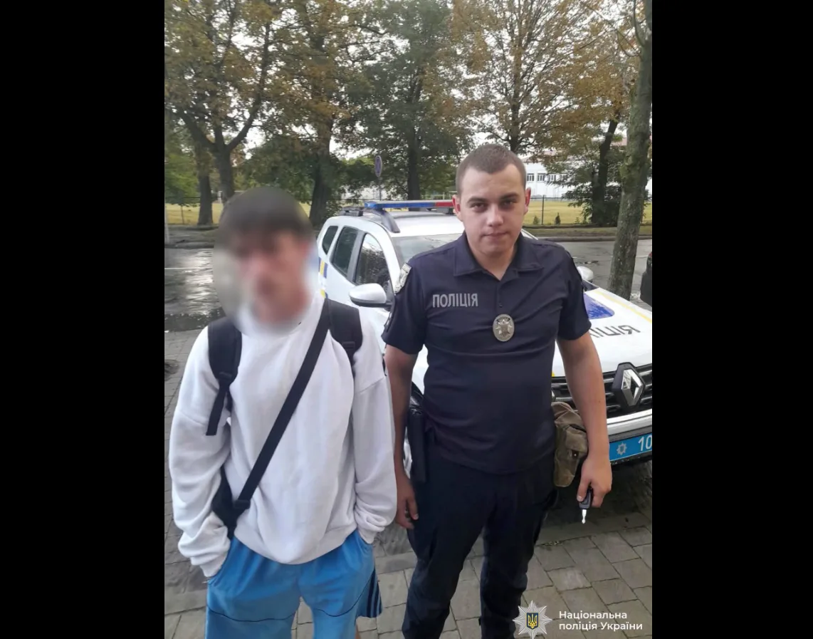 Поліцейський стоїть поруч із чоловіком біля патрульного авто