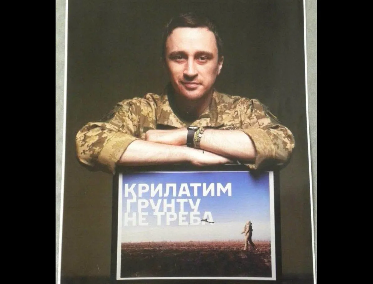 Військовий у камуфляжі тримає плакат про крилаті ґрунту