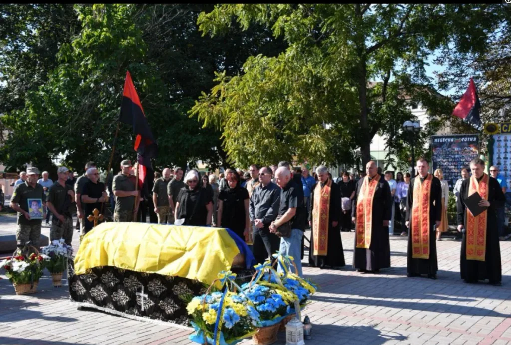 Прощання з військовим біля труни, вкритої українським прапором