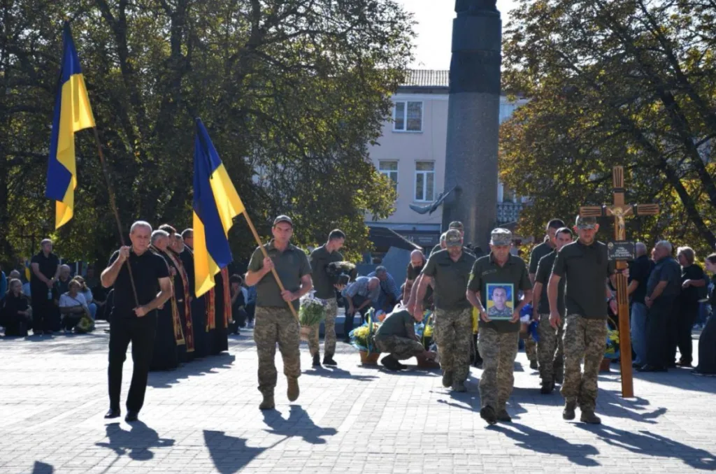 Похоронна процесія військового з прапорами та хрестом