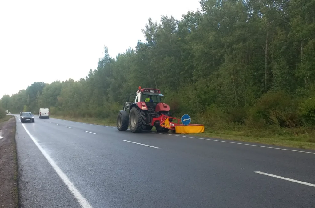 Трактор із дорожнім обладнанням на мокрій лісовій трасі